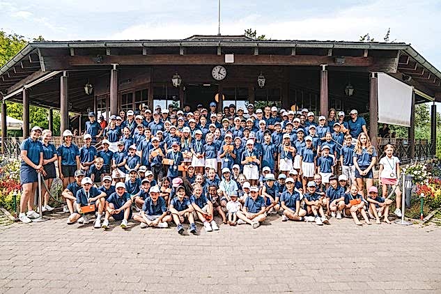 100 Kinder in dunkelblauen Polos stehen beim Jugendpreis des Präsidenten vor dem Halfway House I