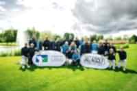 Eine Gruppen von Golferinnen und Golfern des Golf Club St. Leon-Rot stehen bei bewölktem Himmel auf einer Golfbahn als Gruppe zusammen 