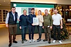 Gruppenfoto im Foyer des GC SLR mit verschiedenen Vertreter mit Präsentation der gerahmten Golf und Naturkunde, die Moritz Lampert und Cordula Humbert hält