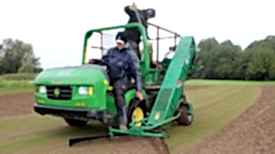 Person fährt mit John Deere Maschine über Golfplatz